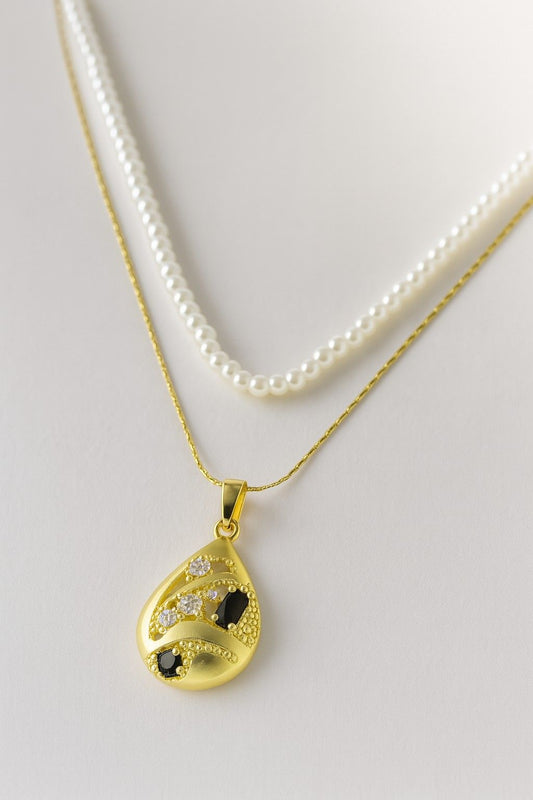 Dual chain necklace with white pearl strand and gold tear-drop pendant featuring black and white stones - ideal for party or festive occasions