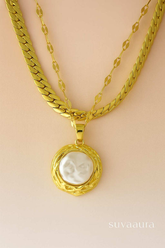 Triple-layer gold-plated necklace with large raw pearl pendant on beige background – perfect for festive and elegant occasions