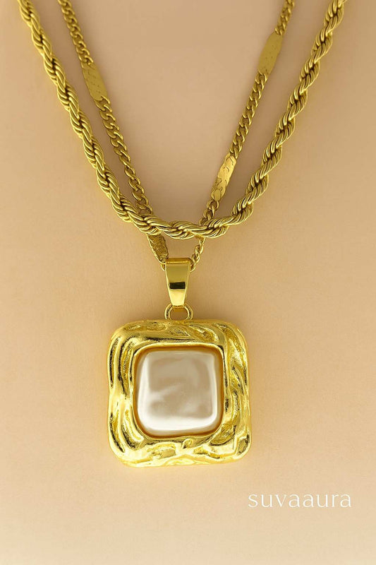Triple-layer twisted rope gold necklace with square pearl pendant on beige background – modern Indo-western design