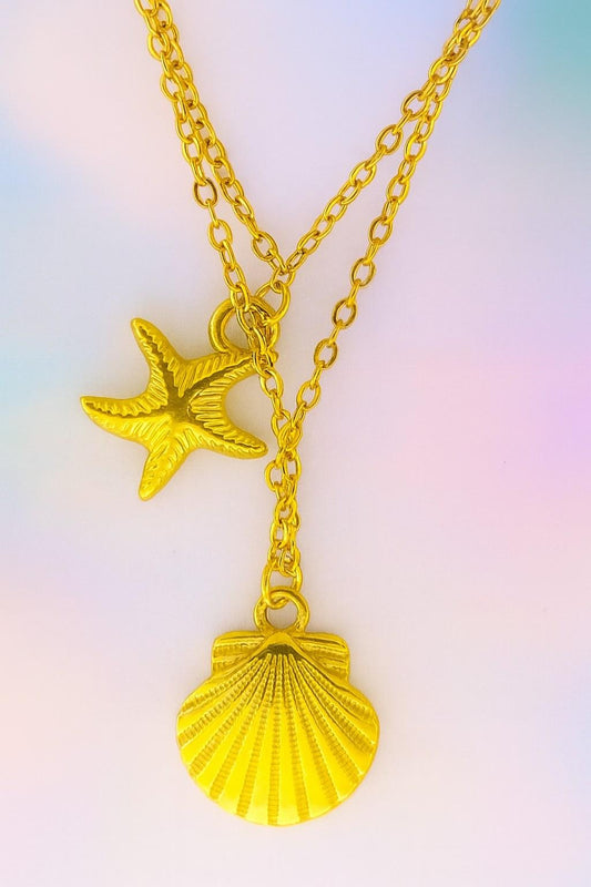 Double-layer gold beach necklace with starfish and shell charm pendants on gradient background – summer boho jewellery by Suvaaura