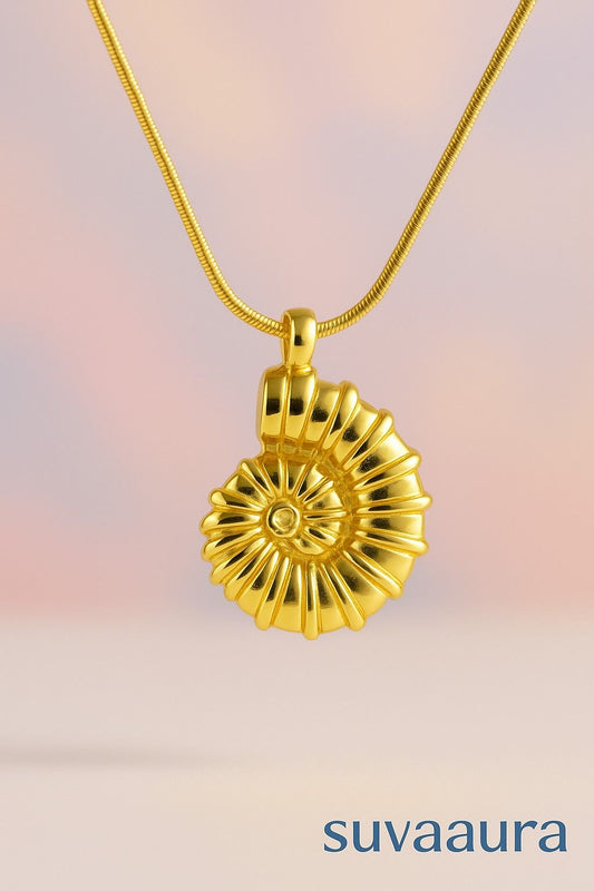 Golden spiral shell pendant necklace with snake chain on soft gradient background – artistic and bold design from Suvaaura