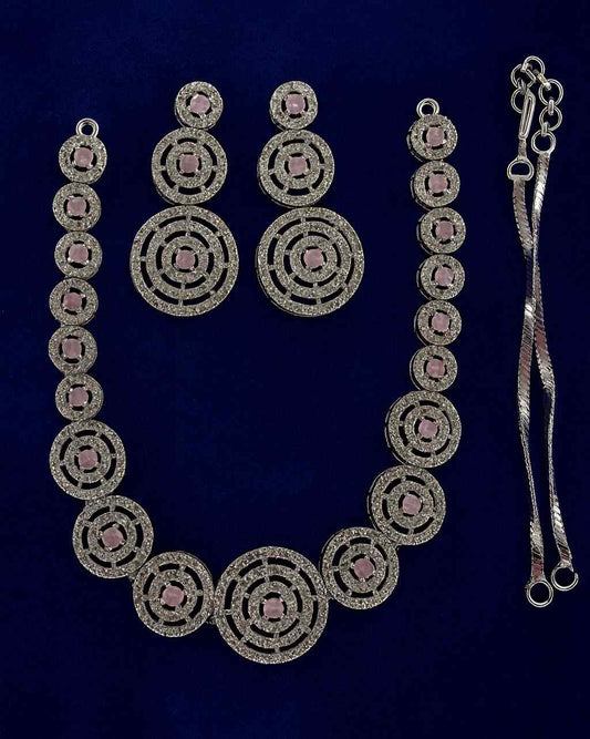 Golden finish circular necklace & earrings set with pink stones on navy background