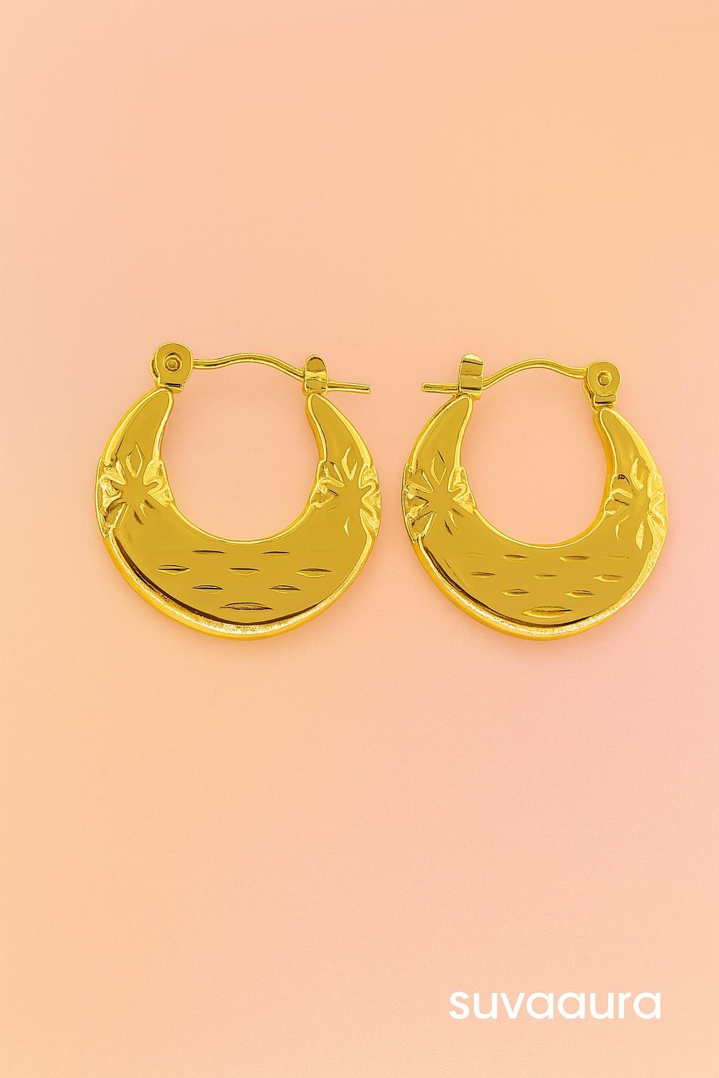 Gold-plated moon-shaped hoop earrings with ethnic floral texture on peach background – festive jewellery by Suvaaura