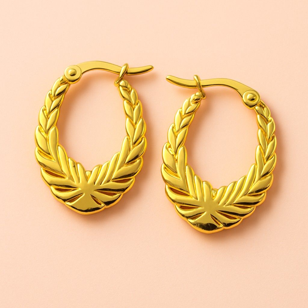 Gold hoop earrings with laurel leaf engraved design – vintage style jewellery on peach background