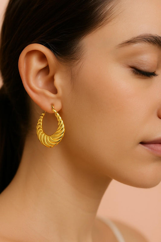 Model wearing twisted spiral gold hoop earrings