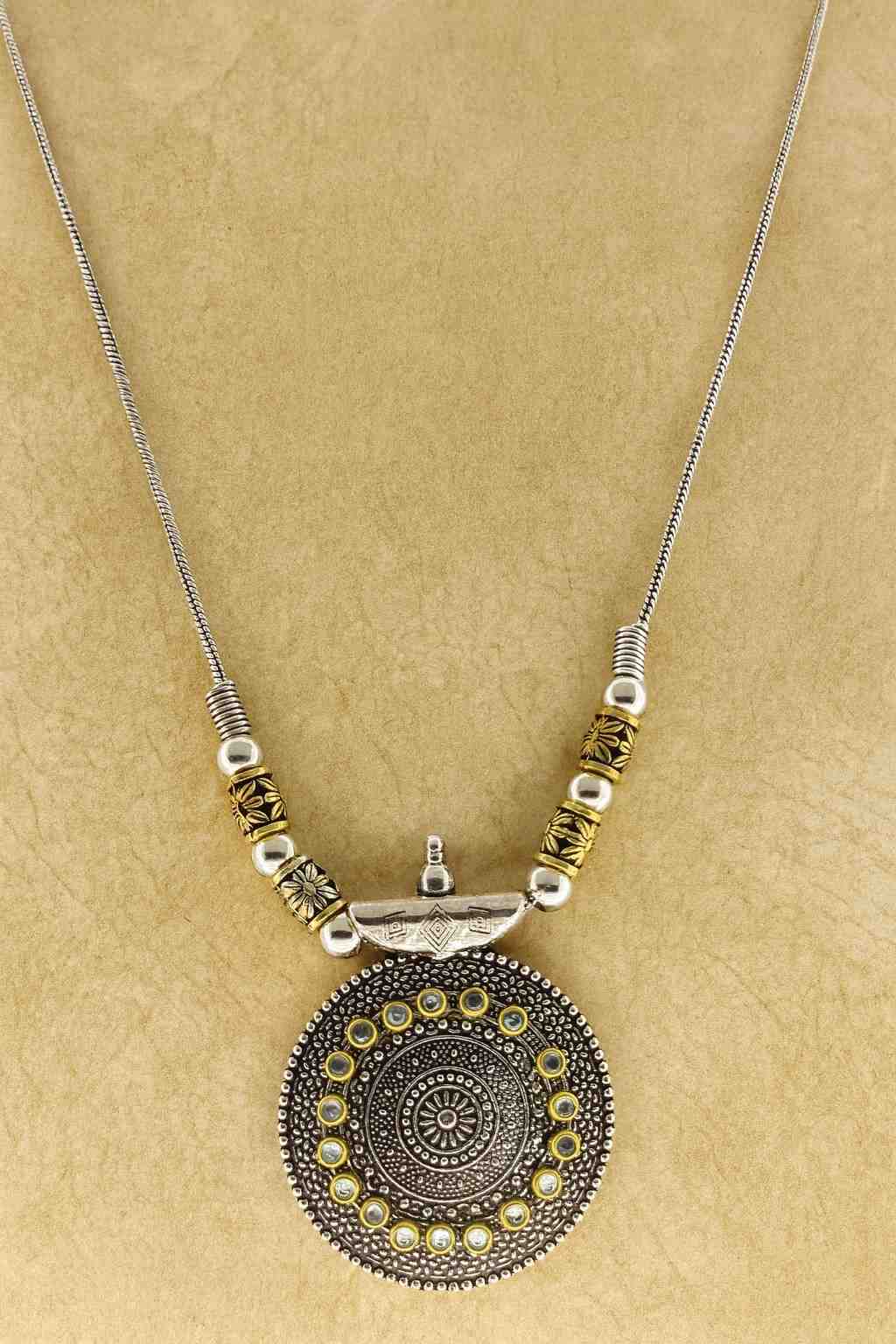 Oxidized silver round pendant necklace with antique golden beads – front view on beige background