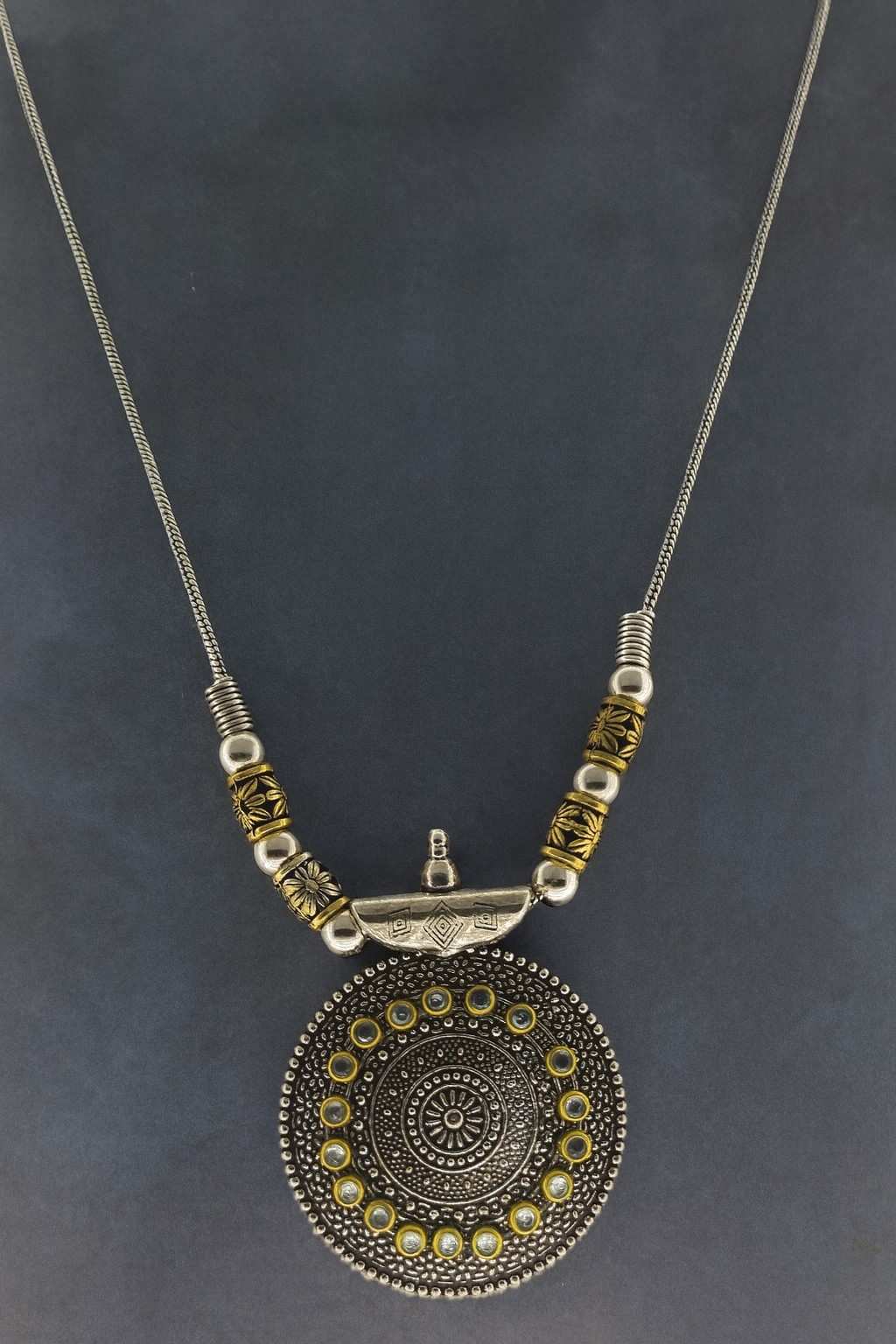 Boho tribal oxidized silver round pendant necklace with golden bead detailing – front view on dark background