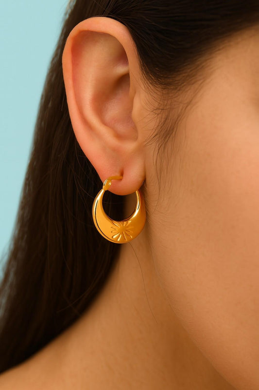 “Model wearing floral engraved gold hoop earrings by Suvaaura”