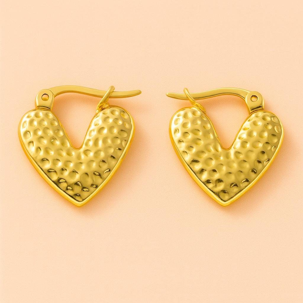 "Heart-shaped hammered gold earrings close-up"