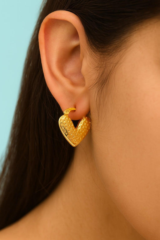 "Model wearing hammered gold heart earrings by Suvaaura"