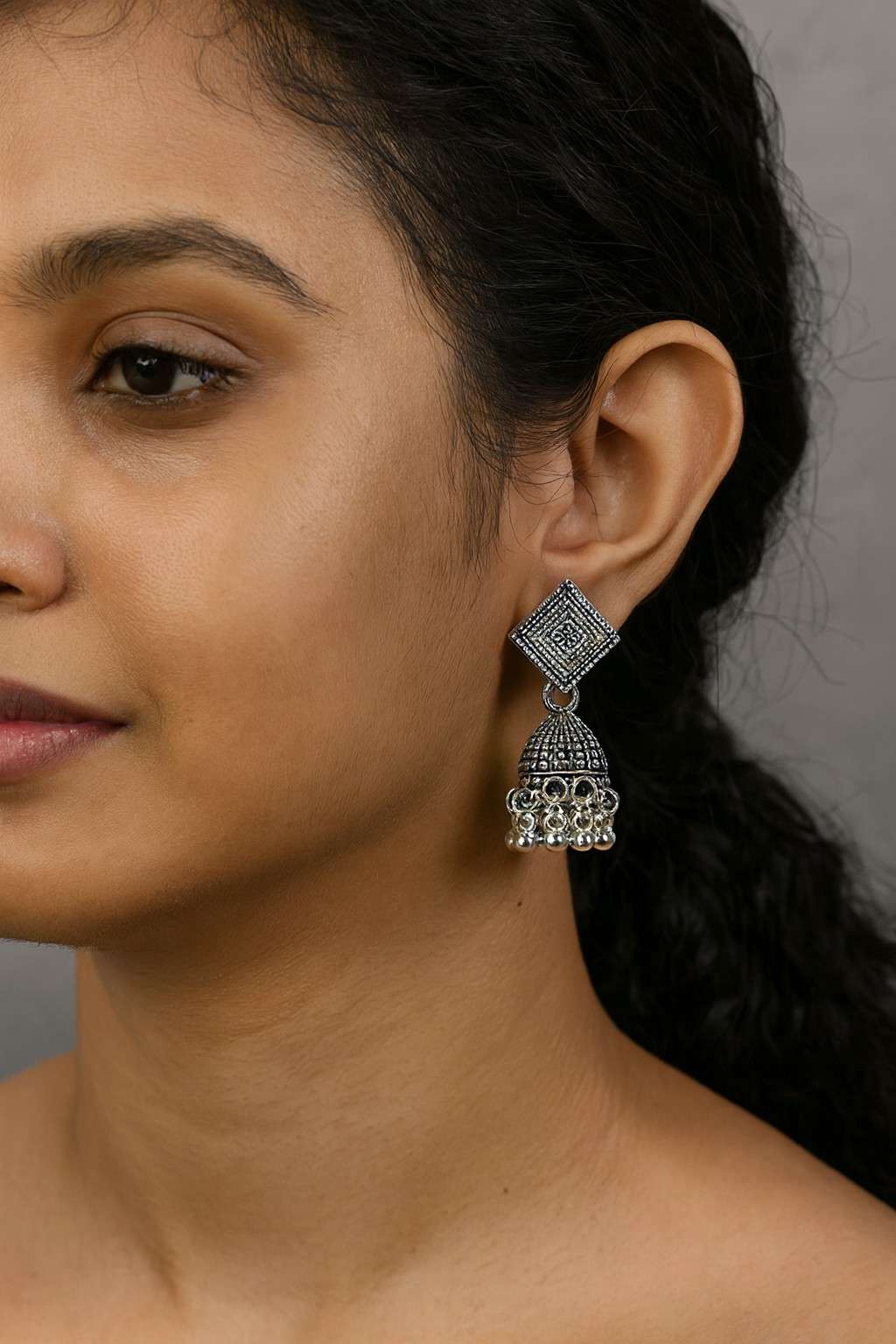 Model wearing antique silver oxidized square stud jhumka earrings