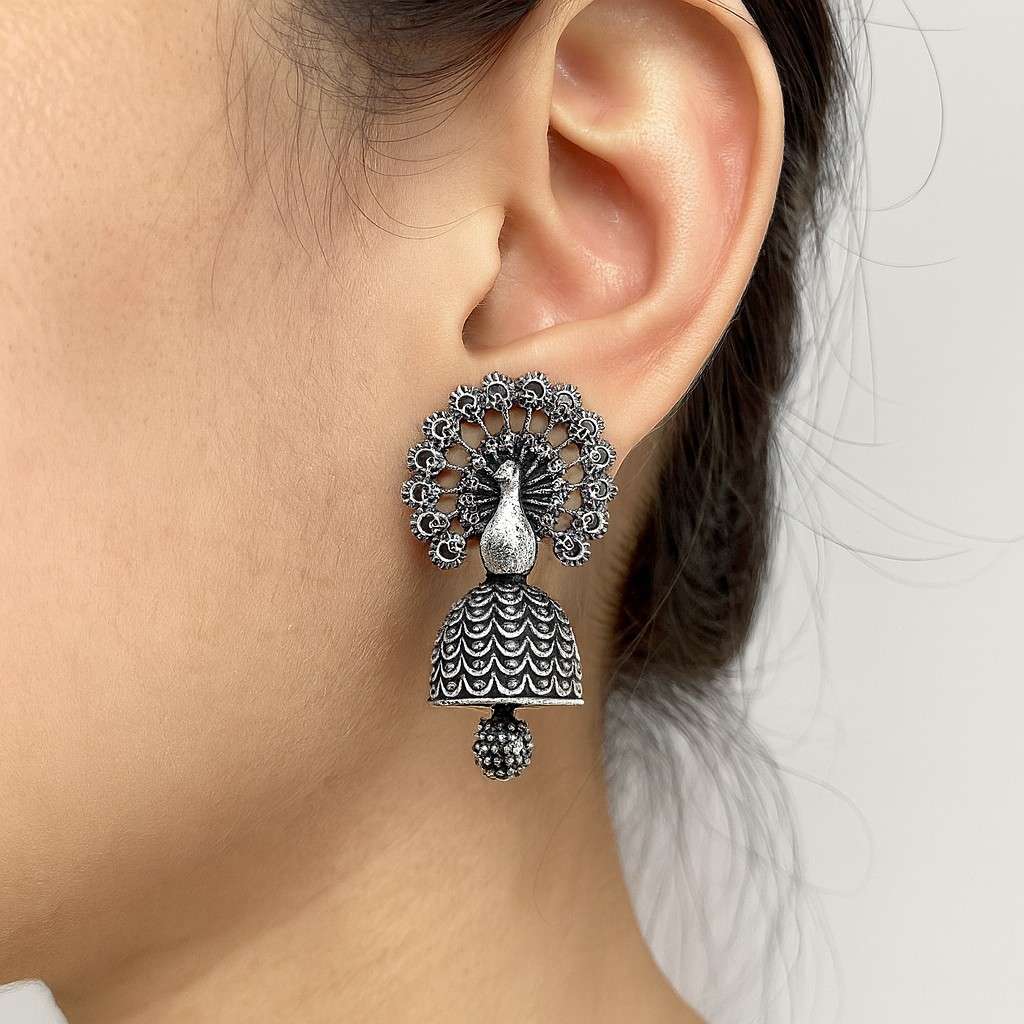 "Peacock design oxidized silver-tone jhumka earrings worn on ear"