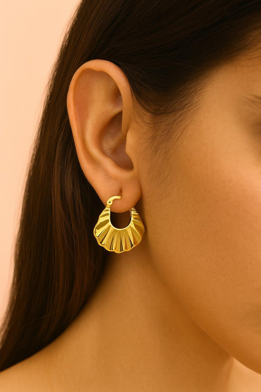 "Model wearing shell-inspired gold-tone earrings by Suvaaura"