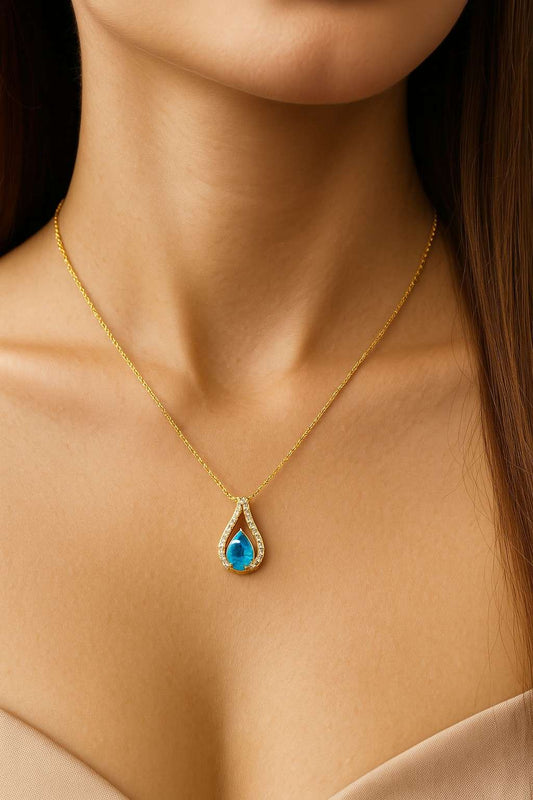 "Model wearing teardrop blue stone gold-tone pendant necklace – Suvaaura"