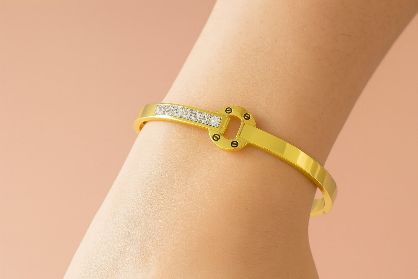 Elegant gold-colored bracelet worn on wrist with circle centerpiece and stones