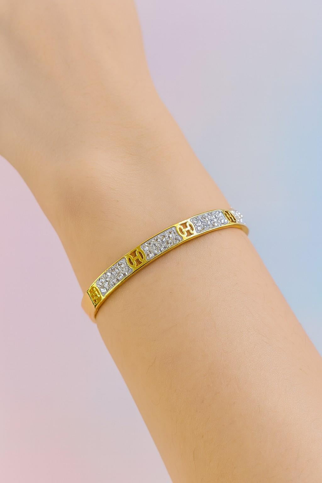 Elegant gold-colored cuff bracelet worn on wrist with sparkling stones