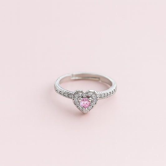 "Model wearing silver-tone ring with pink heart stone and crystal halo"