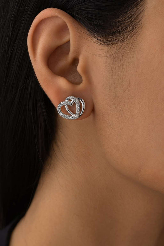Model wearing silver-tone double heart stud earrings with crystals