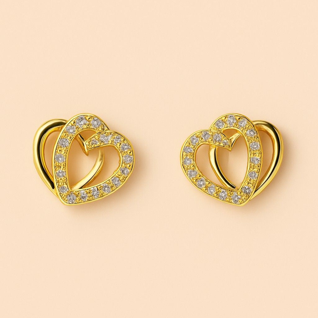 "Gold-tone double heart stud earrings with sparkling stones on plain background"