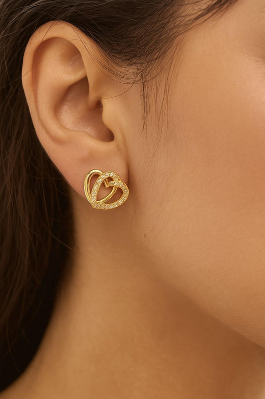 "Model wearing gold-tone double heart stud earrings with shimmering stones"