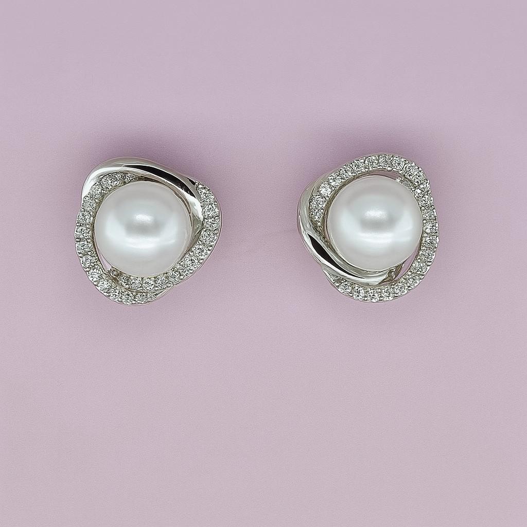 "Silver-tone pearl stud earrings with crystal halo on pink background"