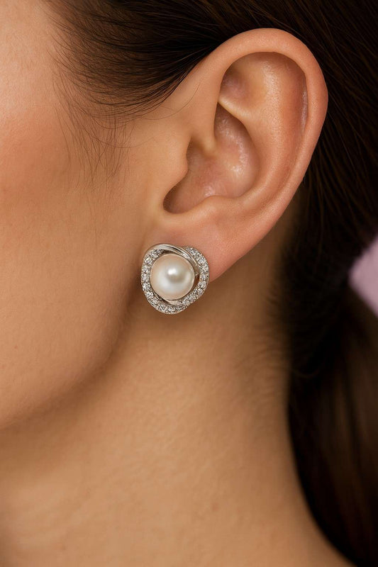 "Elegant silver-tone pearl stud earring worn on ear showcasing crystal halo"