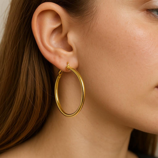 Woman wearing gold-tone large hoop earrings in side profile view
