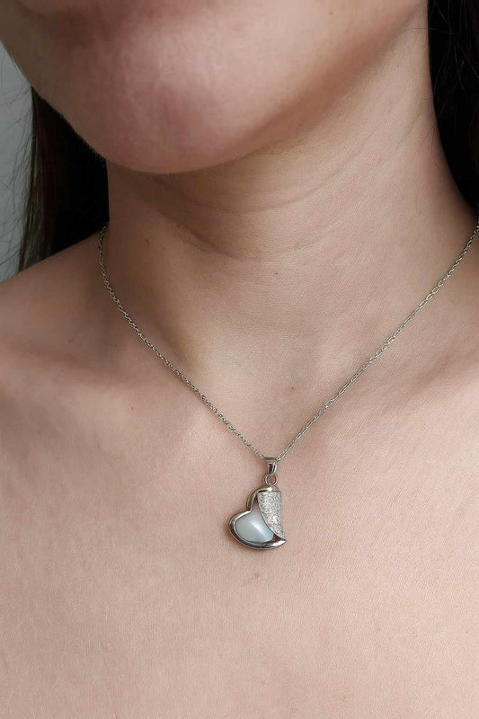 Woman wearing elegant silver-tone heart pendant necklace