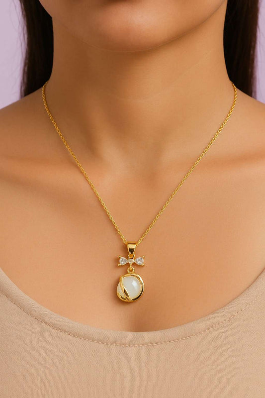 Woman wearing gold-tone bow pendant necklace with white stone