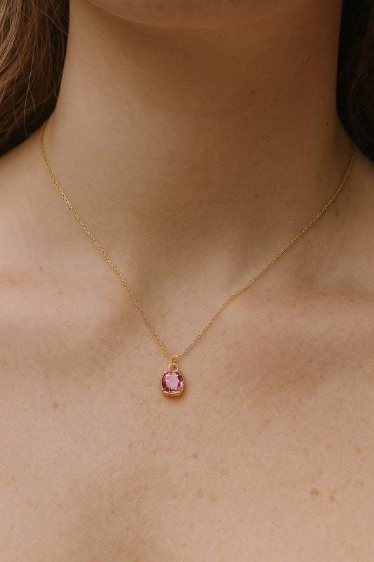 Woman wearing gold-tone necklace with pink cushion cut pendant