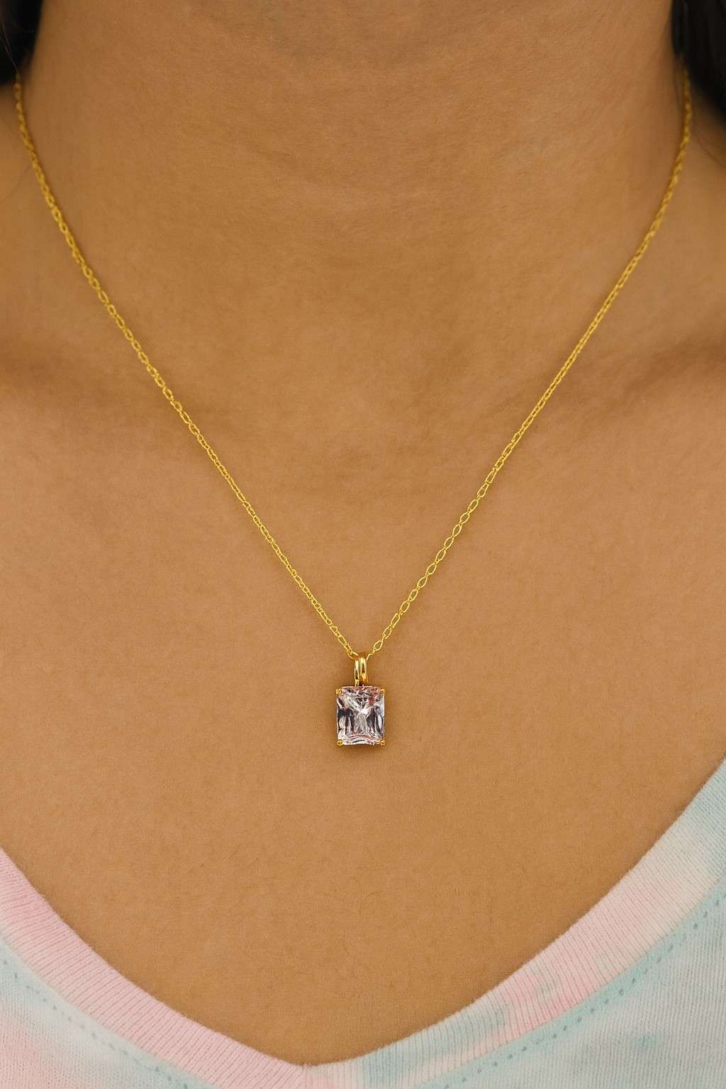 Square-cut crystal pendant necklace worn around neck with gold-tone chain