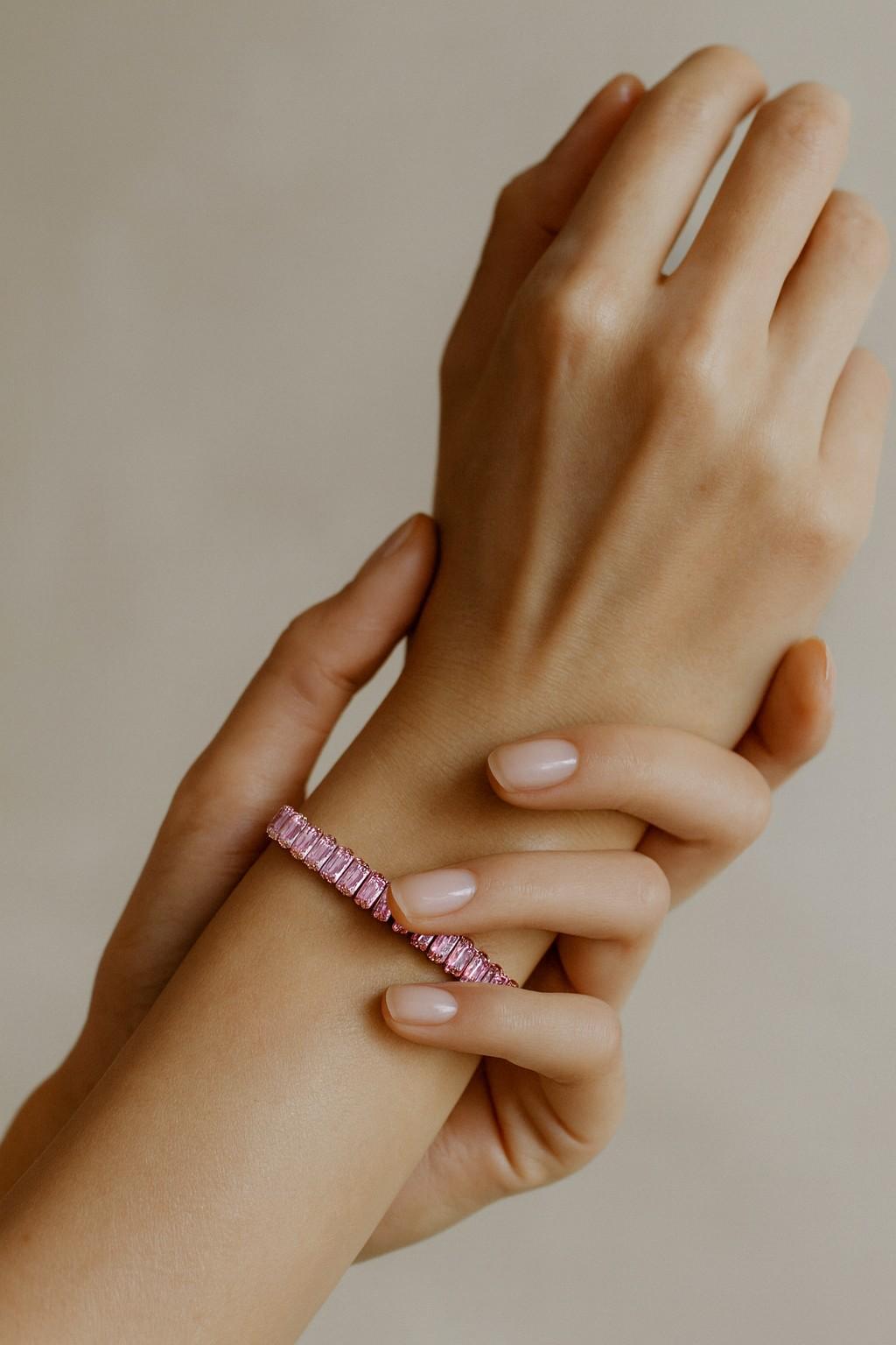 Elegant pink baguette tennis bracelet worn on wrist with rose gold-tone setting
