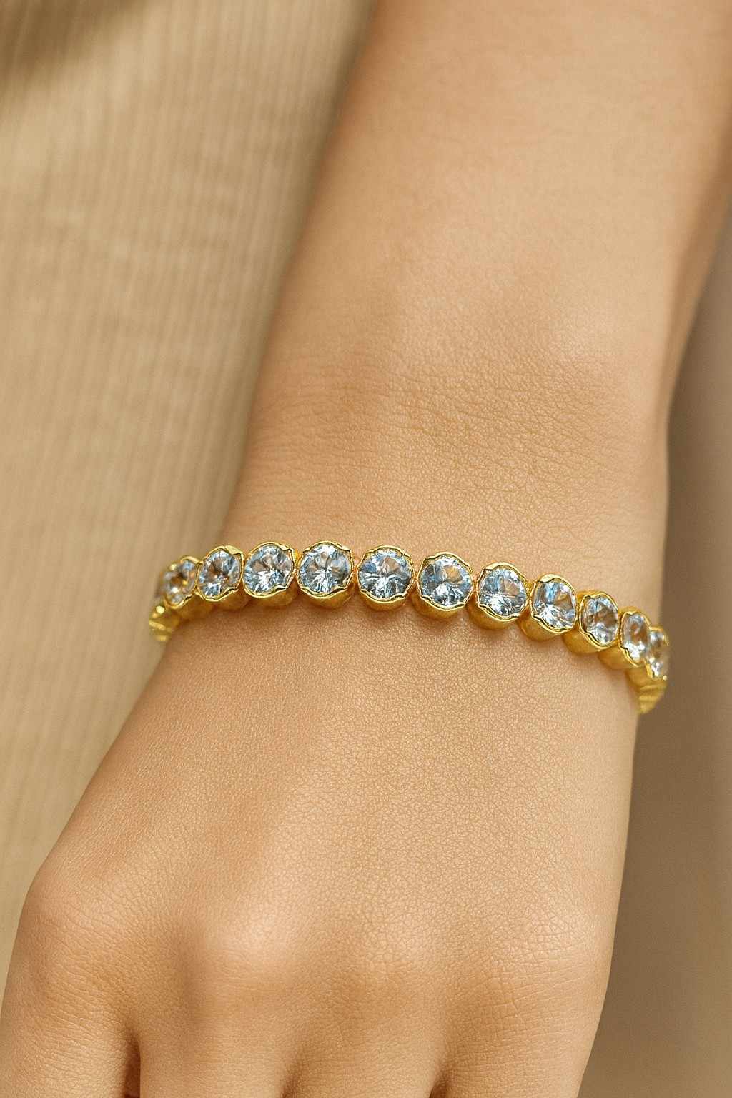 Elegant round-cut crystal tennis bracelet worn on wrist with gold-tone finish