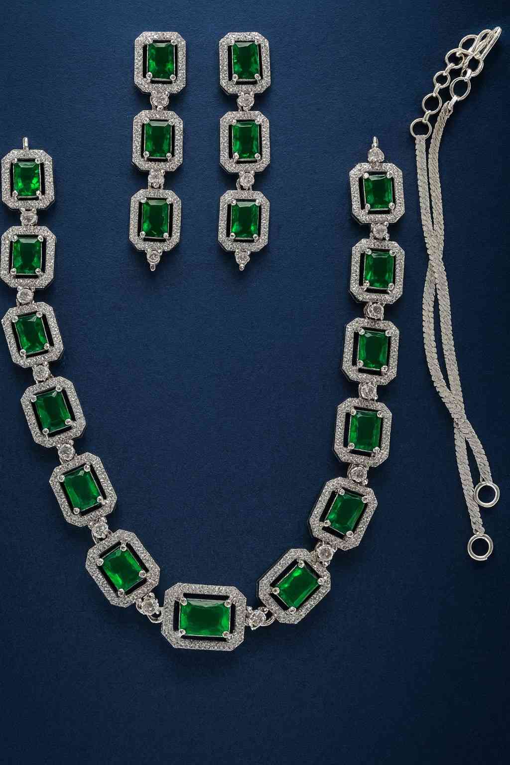 Green American Diamond necklace set with earrings in silver-tone finish on dark blue background