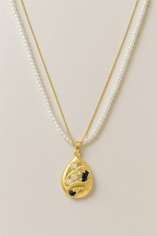 Dual chain necklace with white pearl strand and gold tear-drop pendant featuring black and white stones - ideal for party or festive occasions