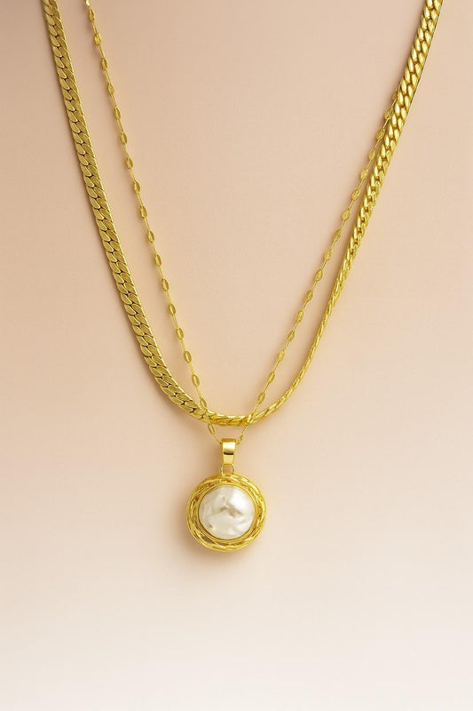 Triple-layer gold-plated necklace with large raw pearl pendant on beige background – perfect for festive and elegant occasions

