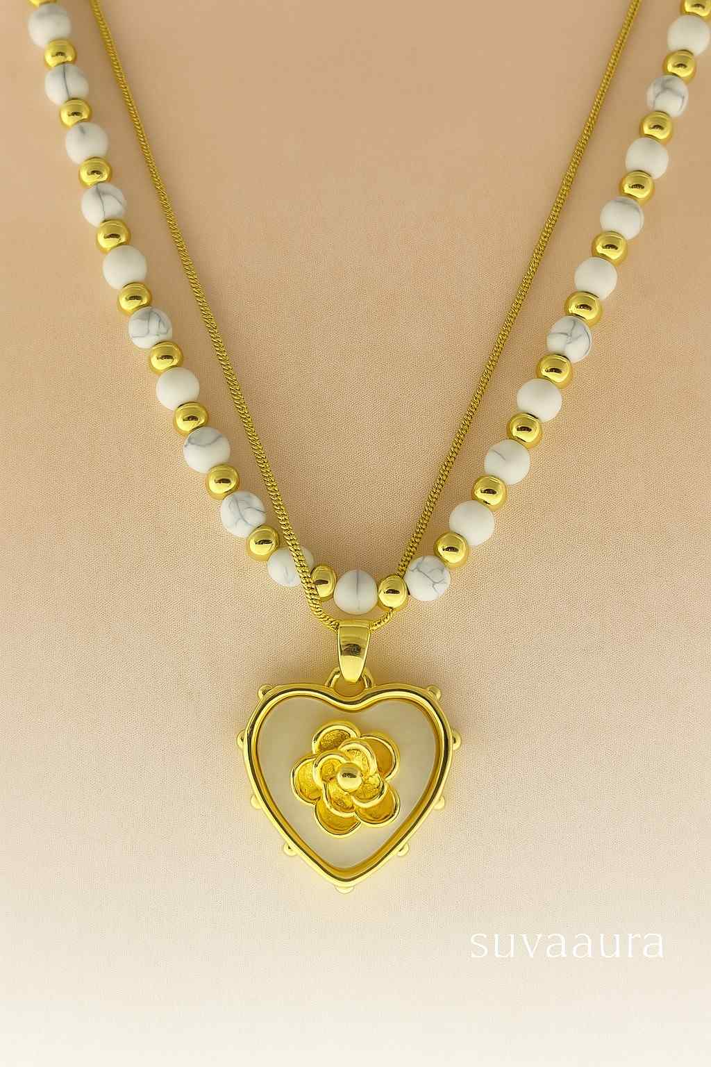 Heart-shaped gold pendant with floral center on dual white and gold bead necklace – Suvaaura romantic jewellery collection

