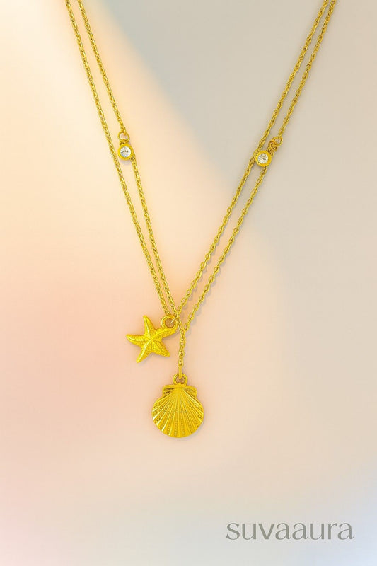Double-layer gold beach necklace with starfish and shell charm pendants on gradient background – summer boho jewellery by Suvaaura