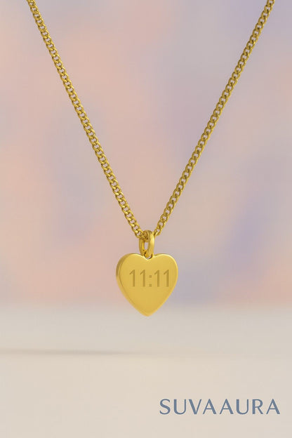 Gold heart-shaped pendant necklace with engraved 11:11 angel number on pastel background – minimalist style from Suvaaura