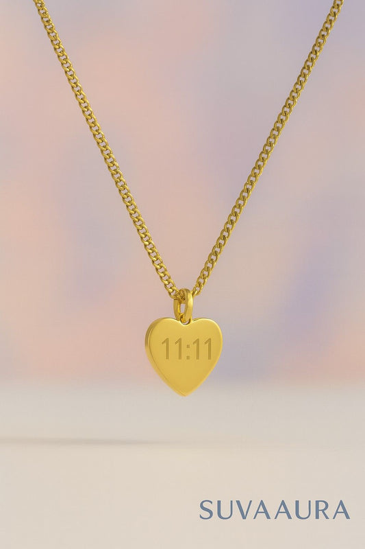 Gold heart-shaped pendant necklace with engraved 11:11 angel number on pastel background – minimalist style from Suvaaura
