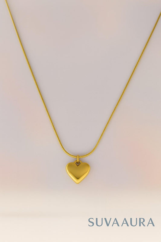 Solid gold heart pendant on sleek snake chain – minimalist love jewellery by Suvaaura on soft pastel background