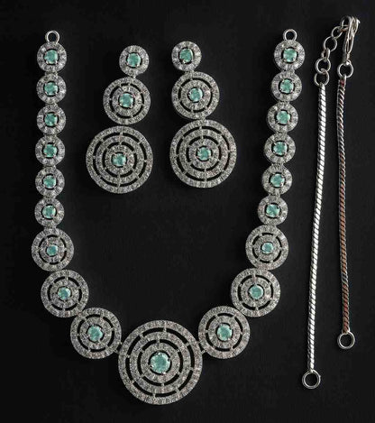 Elegant green stone circular necklace set with American Diamonds in silver-tone finish, featuring matching drop earrings – perfect for weddings and festive wear.