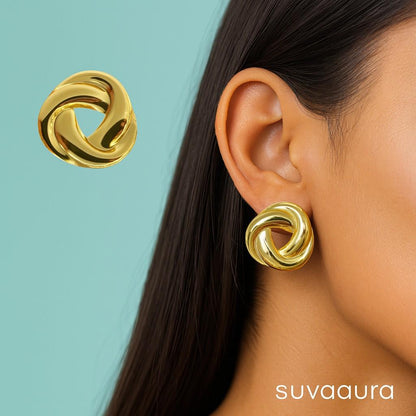 Glossy twisted knot-style round gold stud earrings on peach background – designer minimal earrings by Suvaaura

