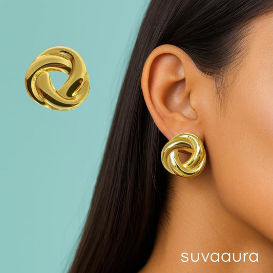 Glossy twisted knot-style round gold stud earrings on peach background – designer minimal earrings by Suvaaura

