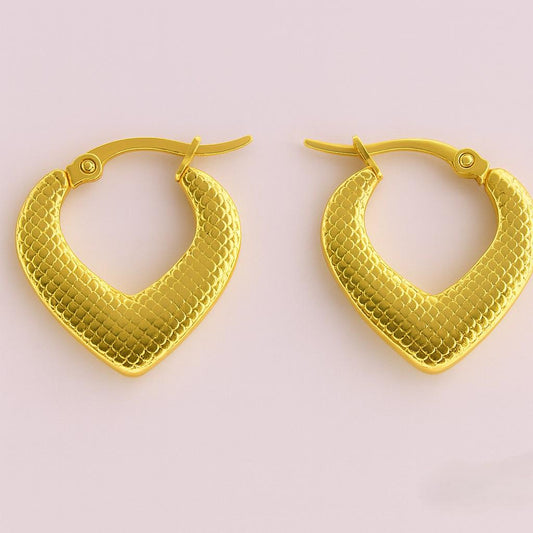 V-shaped textured gold hoop earrings with scale pattern on light pink background – bold fusion jewellery by Suvaaura

