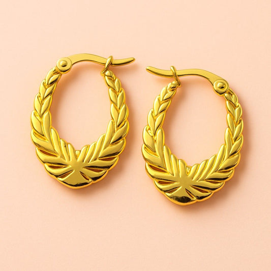 Gold hoop earrings with laurel leaf engraved design – vintage style jewellery on peach background