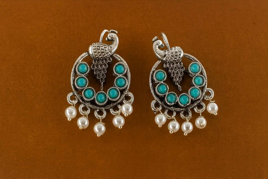 Antique silver peacock earrings with turquoise beads and pearl drops – flat lay view