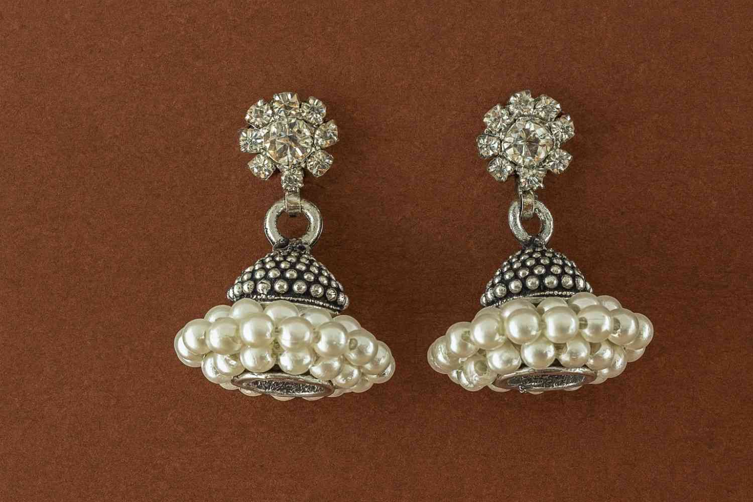 Antique silver floral stud pearl cluster jhumka earrings on white background