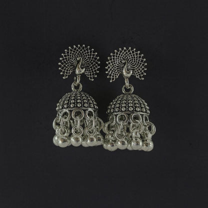 Oxidized peacock design silver-tone jhumka earrings with hanging beads on plain background