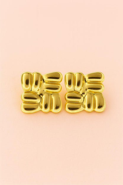 "Glossy gold imitation stud earrings on peach background – Suvaaura"


